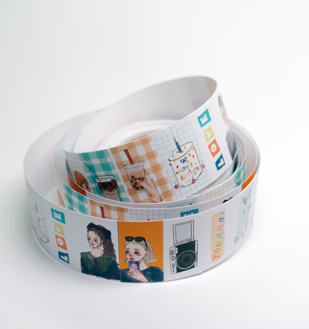 A roll of decorative washi tape with colorful printed illustrations and text, coiled on a plain white background.